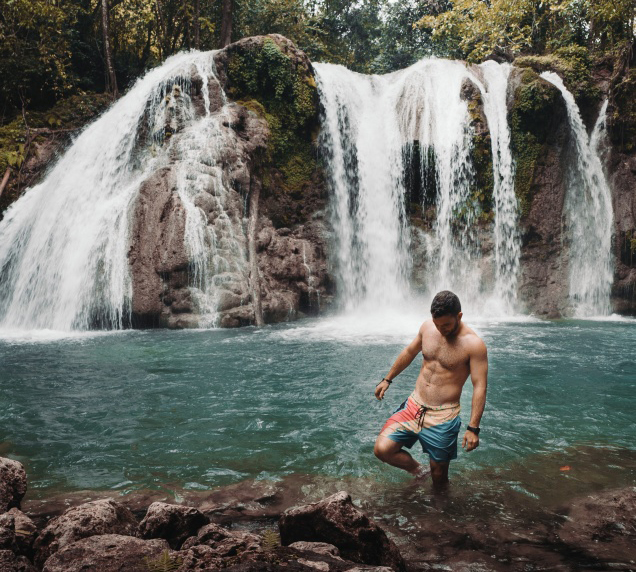 Young man wading in a waterfall.